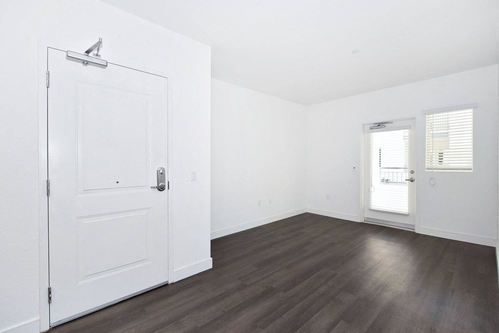 an empty room with white walls and wood floors and a white door