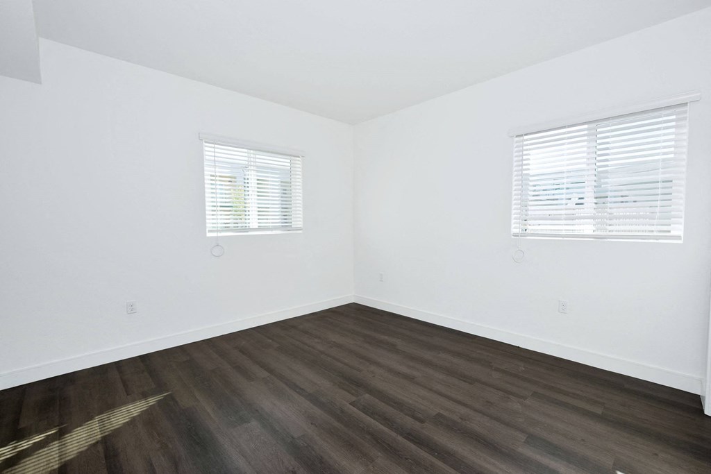 an empty room with white walls and wood floors