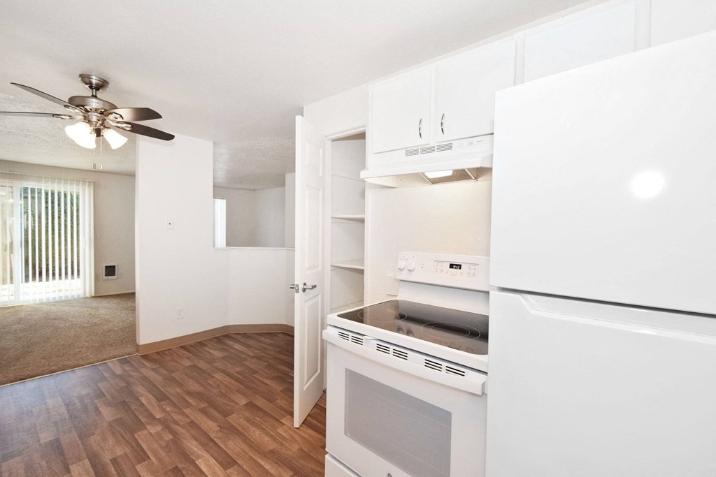 a renovated kitchen with white appliances and a ceiling fan