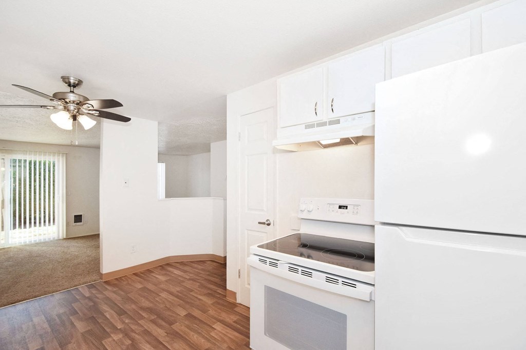 a kitchen with white appliances and a ceiling fan