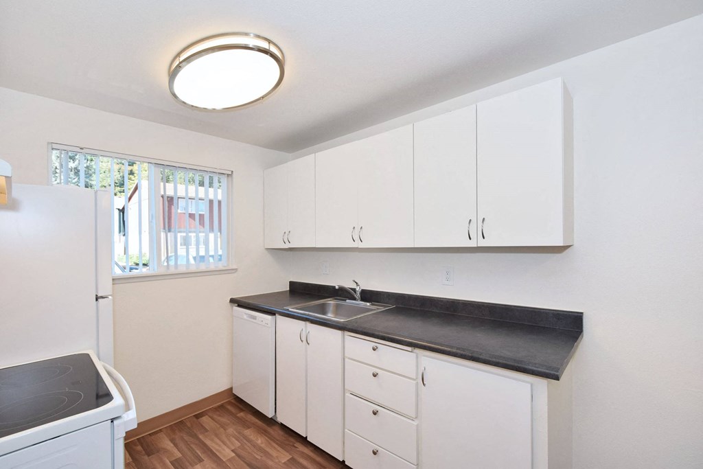 a kitchen with white cabinets and a sink and a window