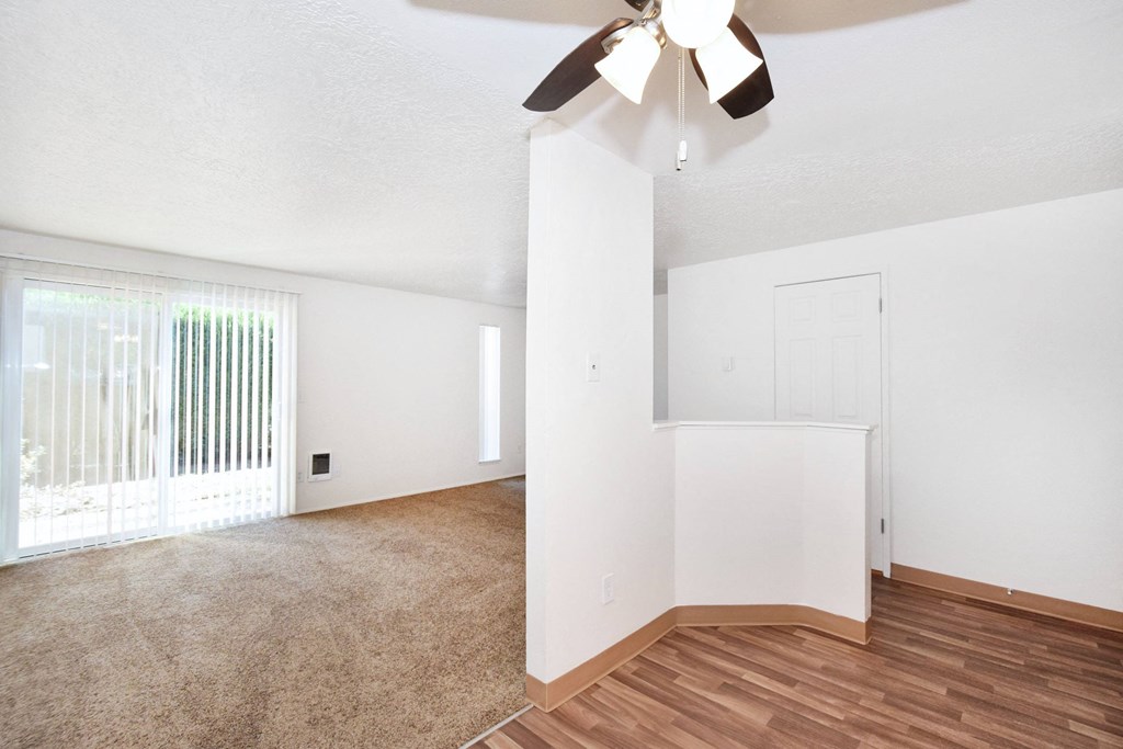 an empty living room with a ceiling fan and a window