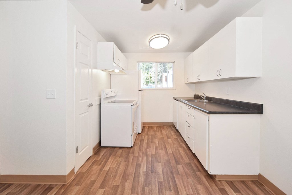 a kitchen with white cabinets and a sink and a window