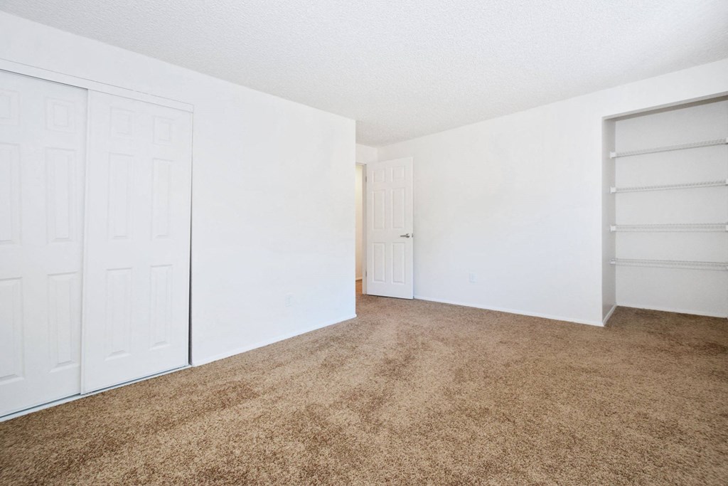 an empty bedroom with white walls and carpet and a closet