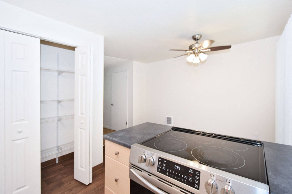 a kitchen with a stove and a ceiling fan
