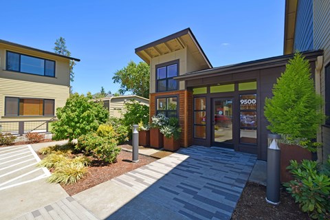 A modern building with a glass entrance and a stone pathway leading to it.