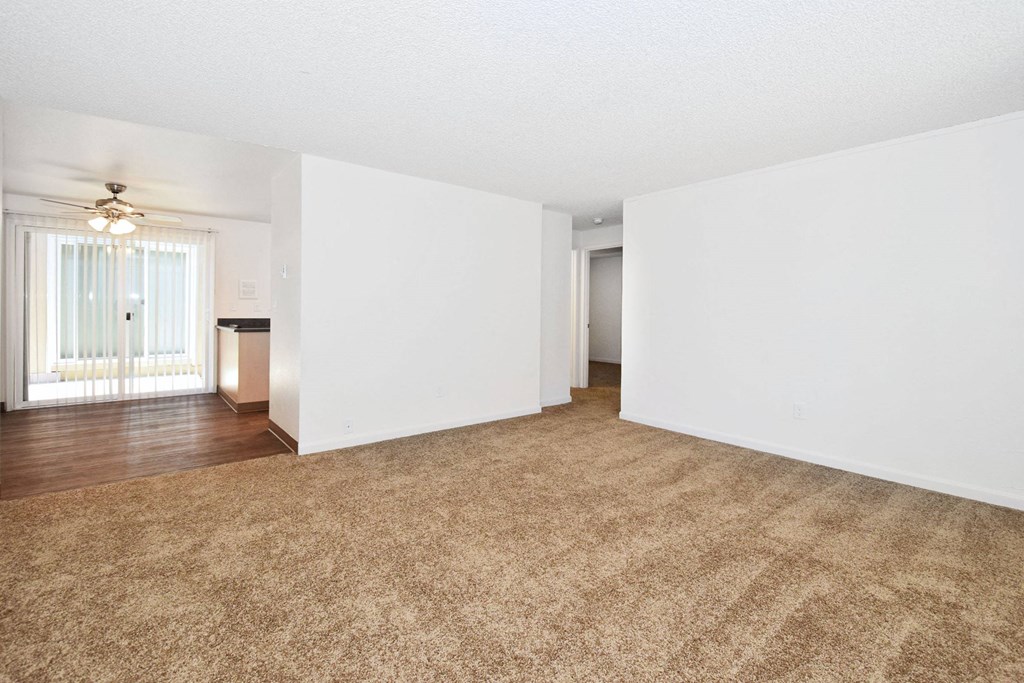 an empty living room with white walls and a ceiling fan
