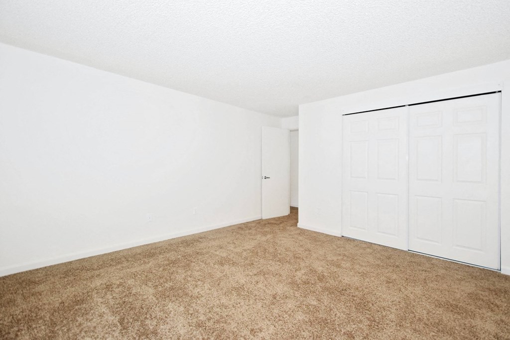 an empty living room with a door to a closet