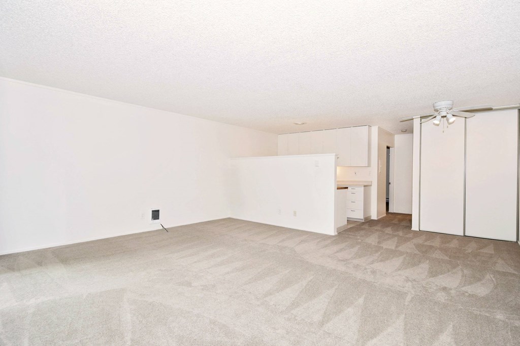 an empty living room with white cabinets and a white refrigerator