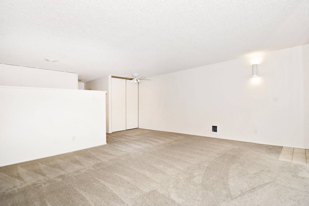 an empty living room with white walls and a tile floor