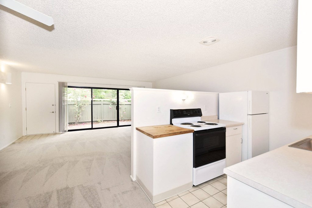 an empty kitchen with white cabinets and a black stove