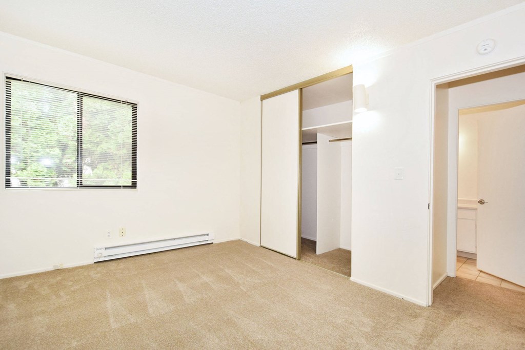 an empty living room with a window and a closet