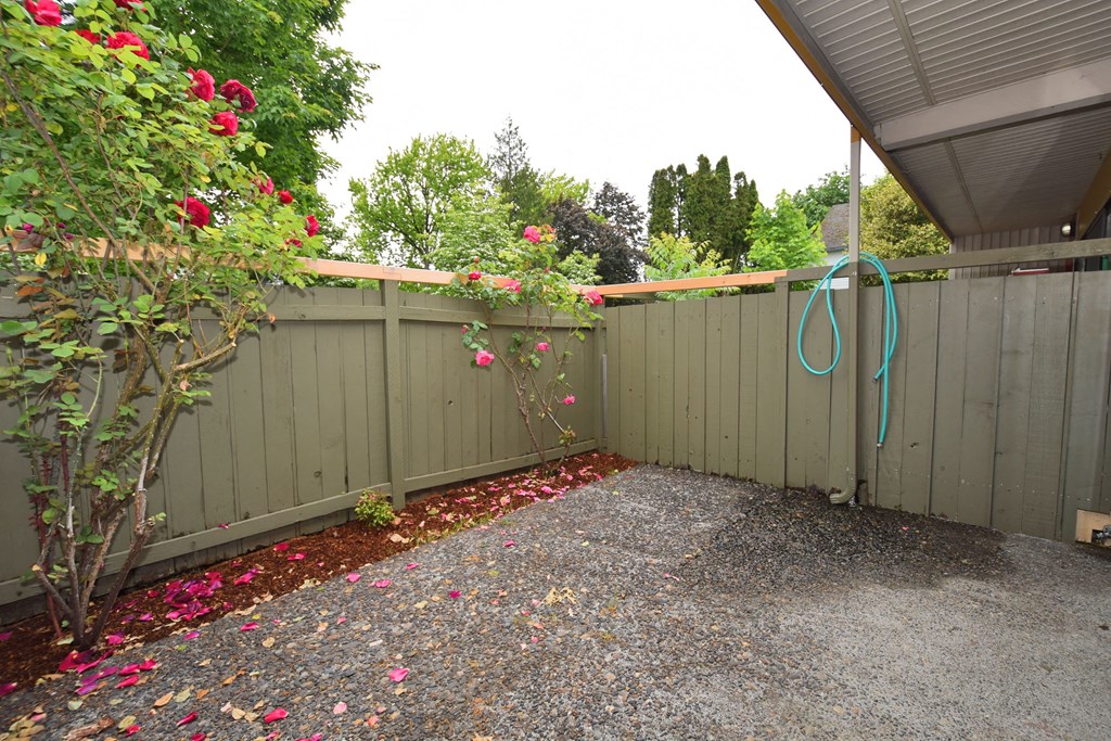a backyard with a fence and a garden with pink flowers