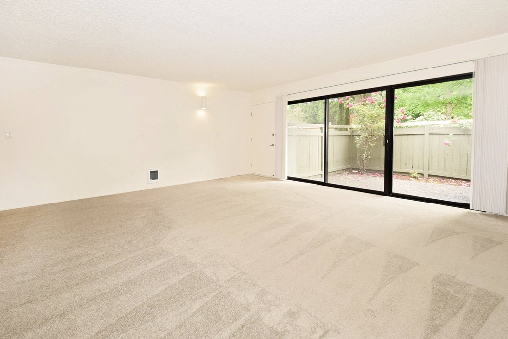 an empty living room with a sliding glass door to a patio