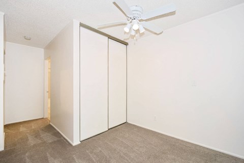a bedroom with white walls and a ceiling fan