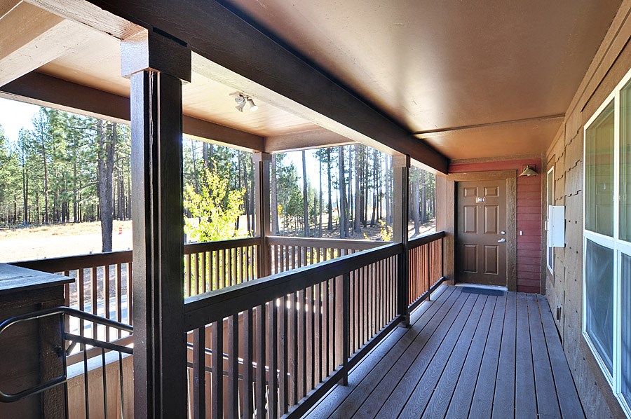 a balcony with a view of a wooded area and a door
