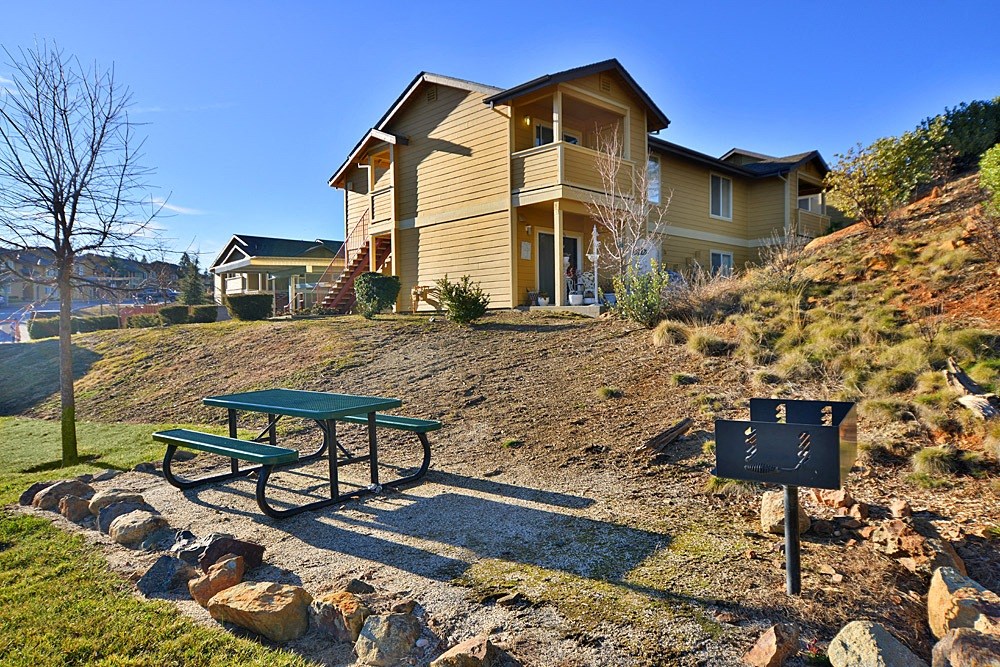 a picnic table sits in front of a house on a hill