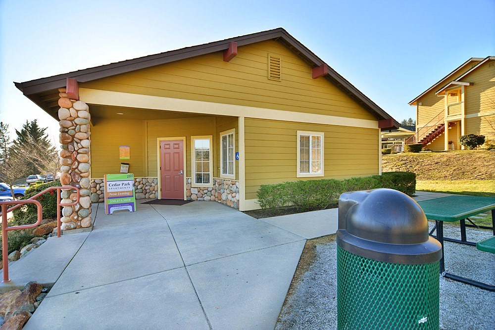 a yellow building with a pink door and a green picnic table in front of it