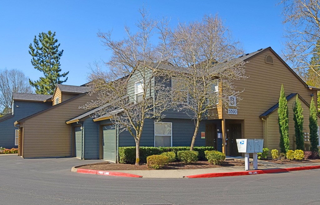 a brown house with green doors and a parking lot