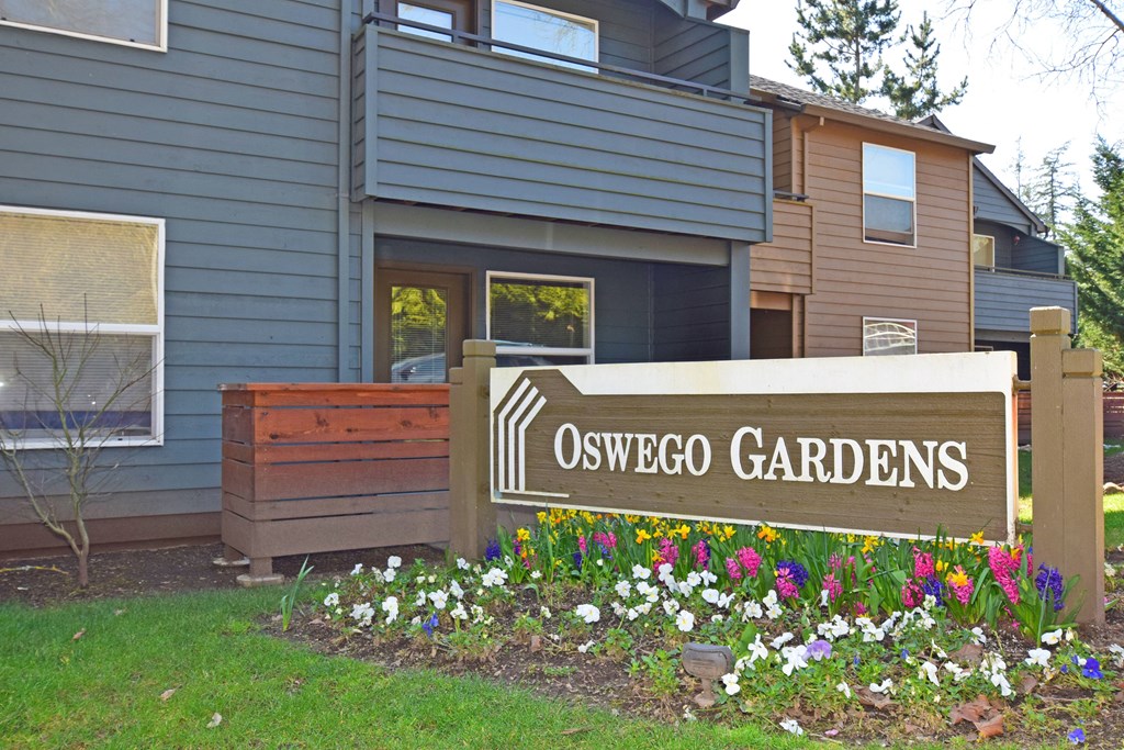 a sign in front of a house with flowers