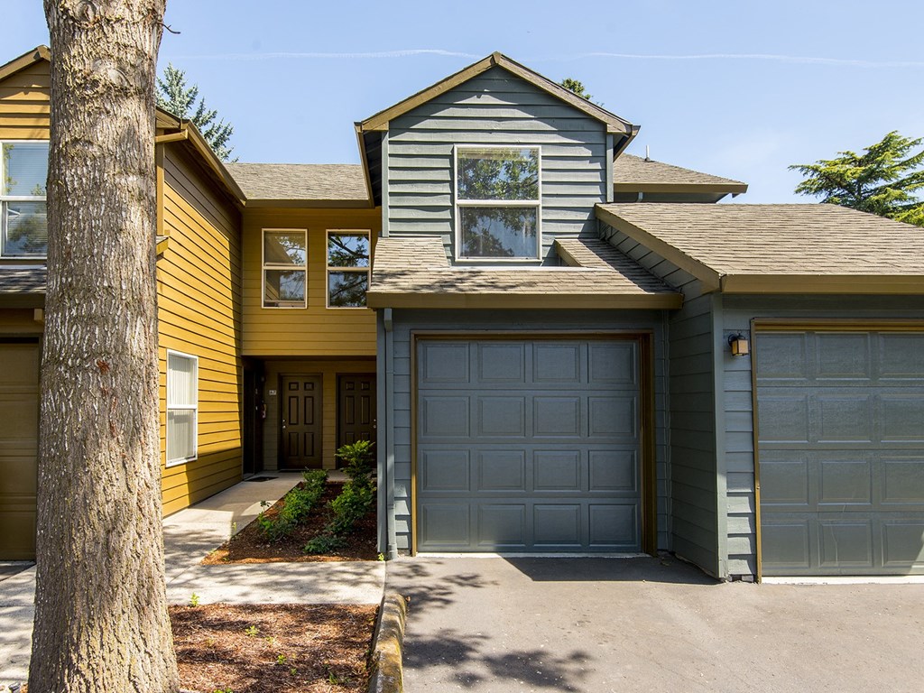 a yellow and with a garage and a tree