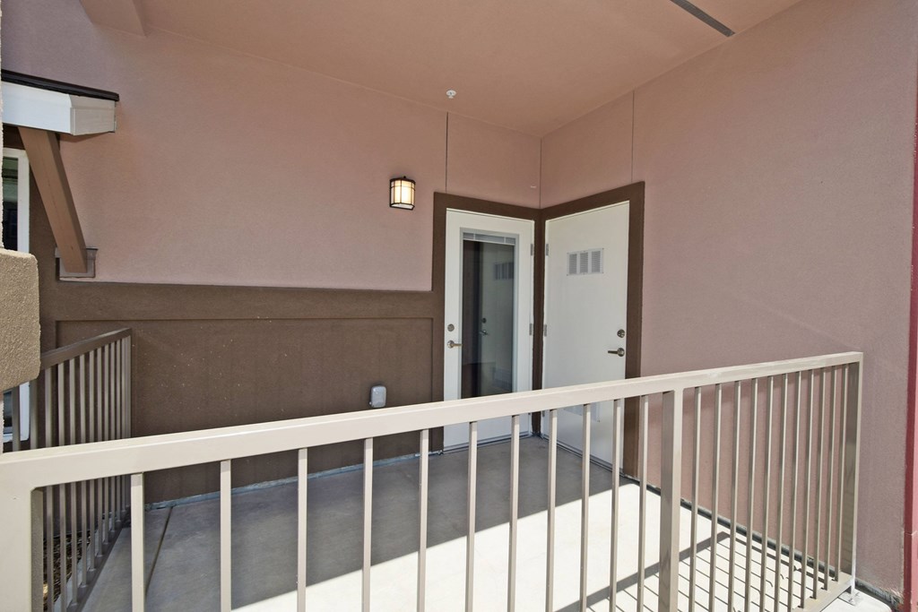 A balcony with a white railing and a door in the background.