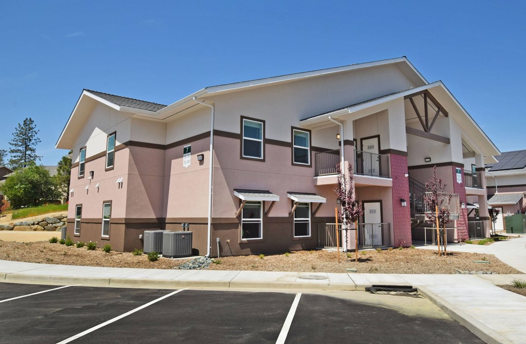 A modern two-story building with a parking lot in front.