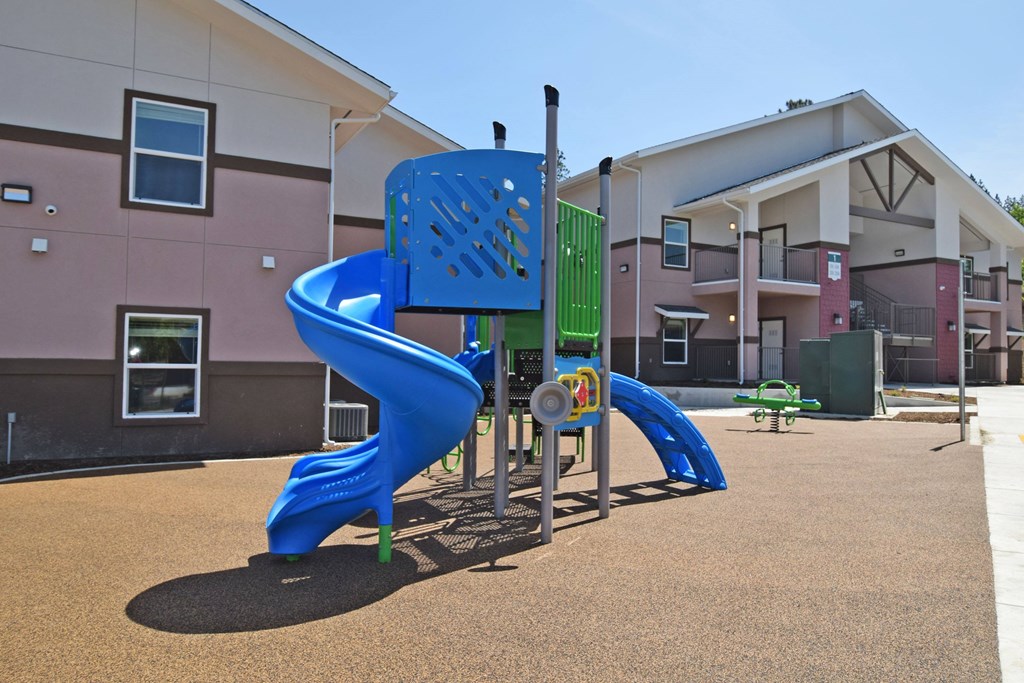 A blue slide in a playground with a brown surface.