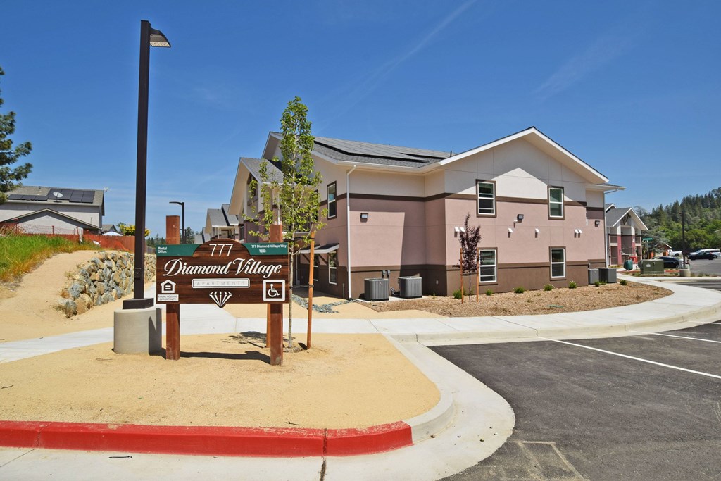A sign for Diamond Village stands in front of a building.