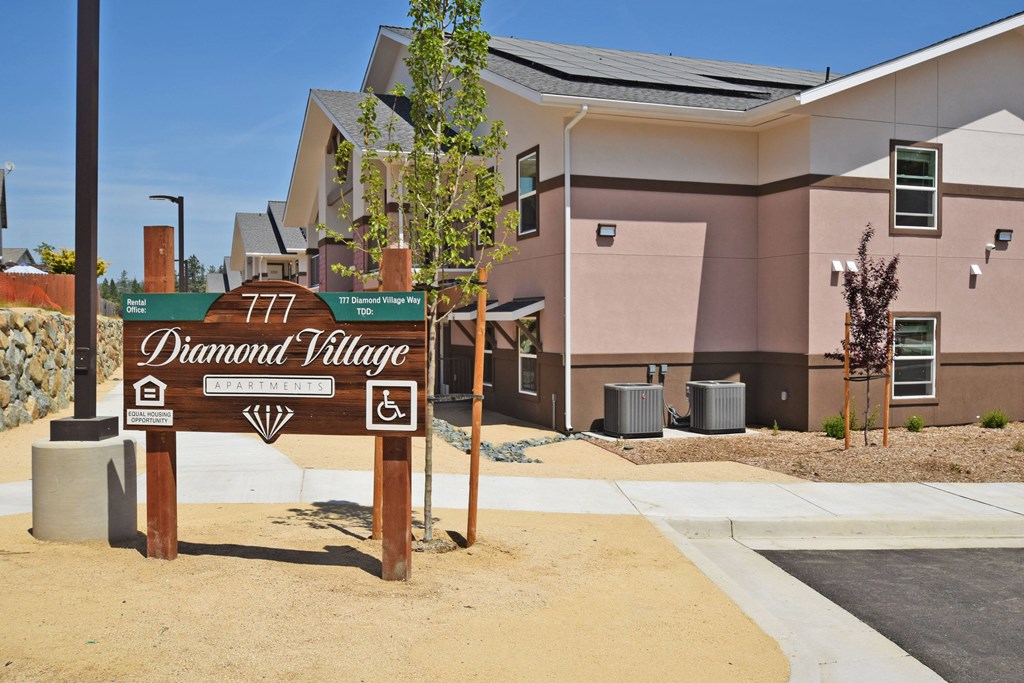 A sign for Diamond Village stands in front of a building.