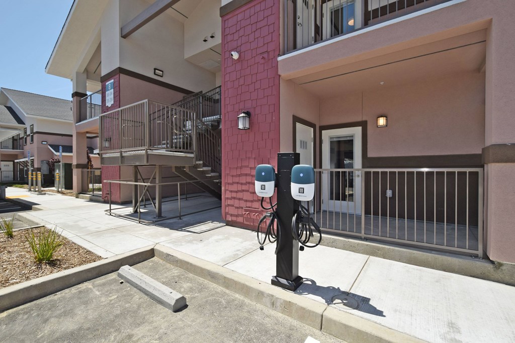 A parking meter is on the sidewalk in front of a building.