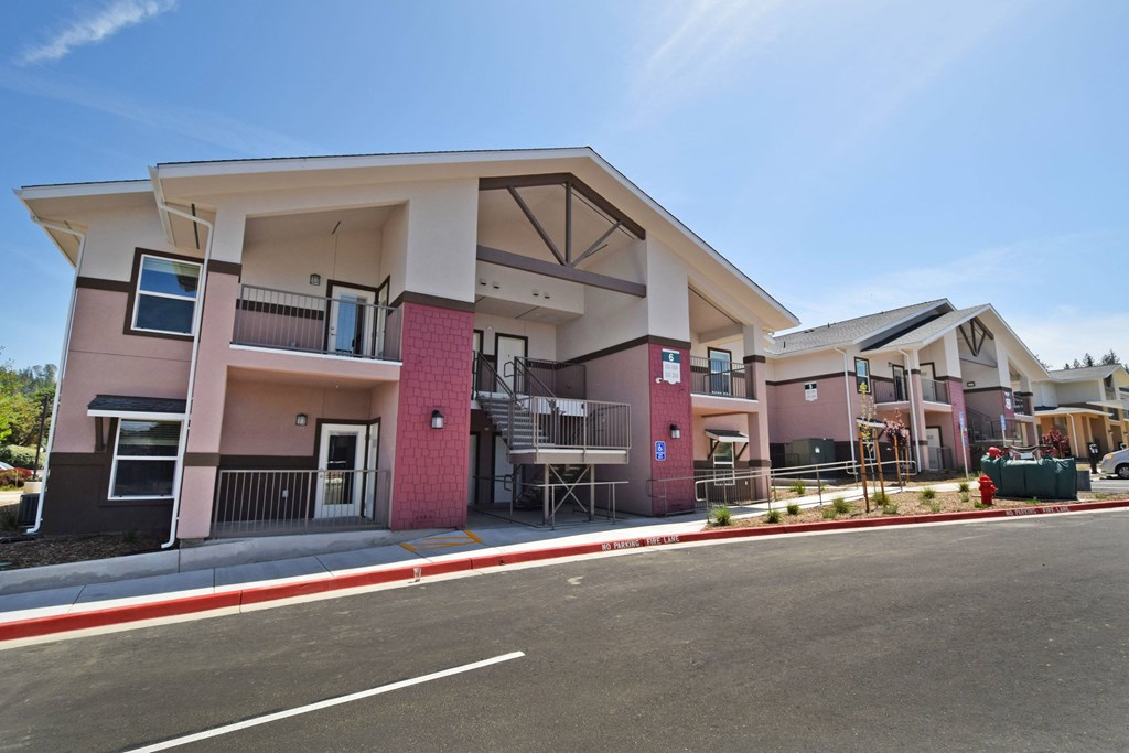 A row of modern townhouses with balconies and a clear blue sky above.