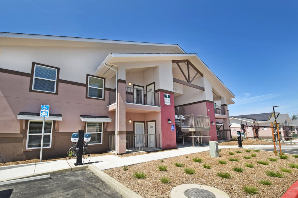 A building with a pink and beige exterior has a bicycle parked in front of it.