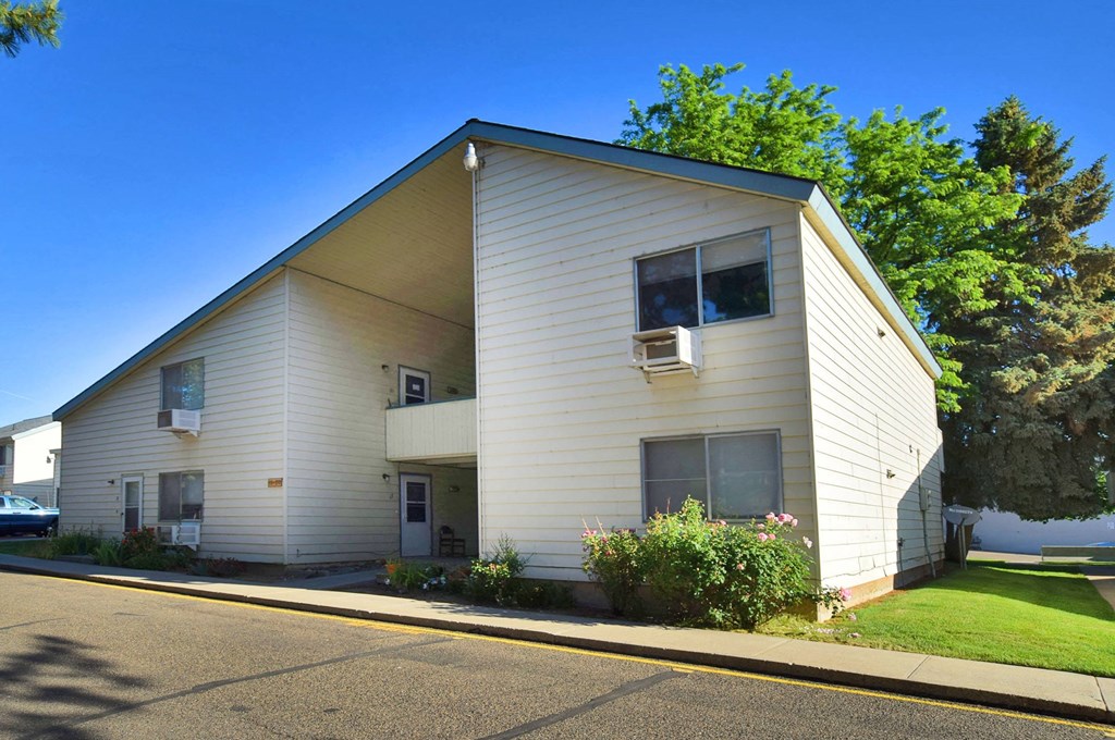 A two-story house with a white exterior and a balcony on the second floor.