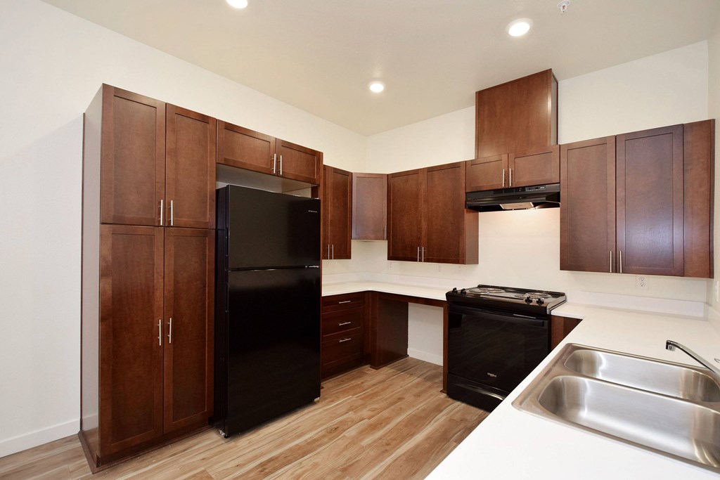 A kitchen with wooden cabinets and a black fridge.