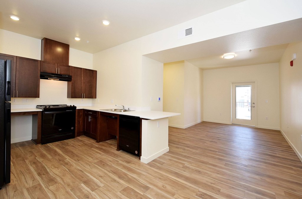 A kitchen with wooden floors and a black refrigerator.