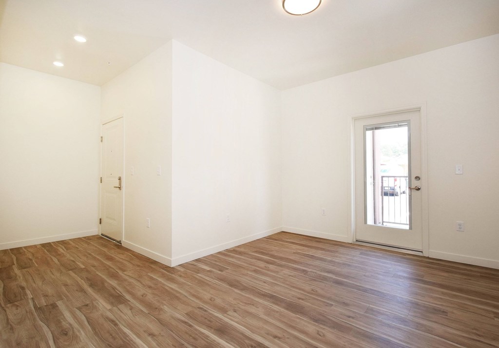 A room with wooden floors and a door on the left side.