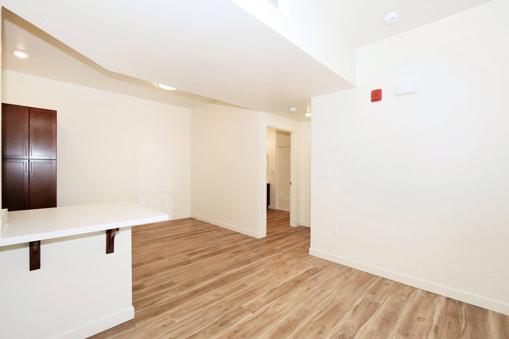 A room with a wooden floor and a white wall with a door.