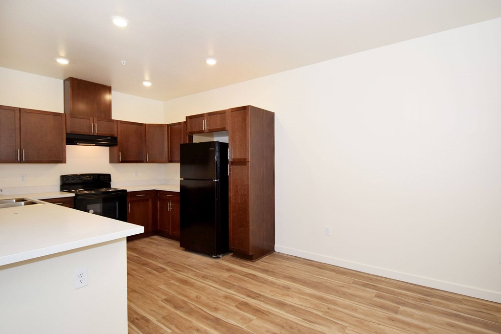 A kitchen with a black refrigerator and wooden cabinets.