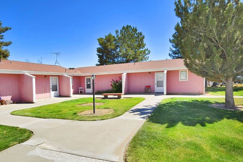 A pink building with a green lawn in front.