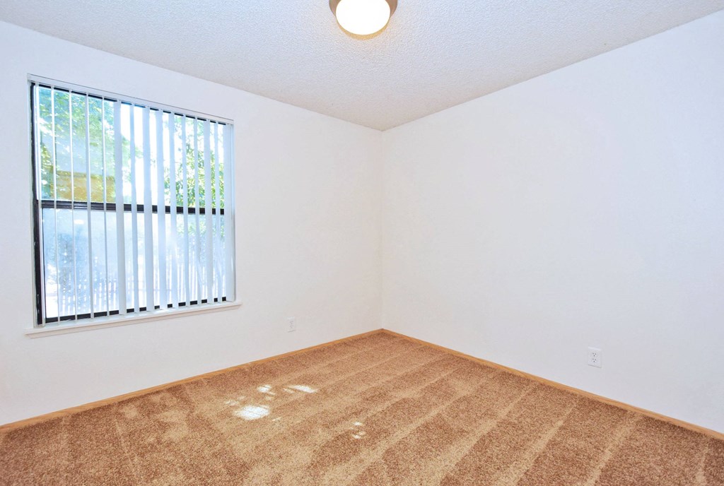 a bedroom with a large window and white walls