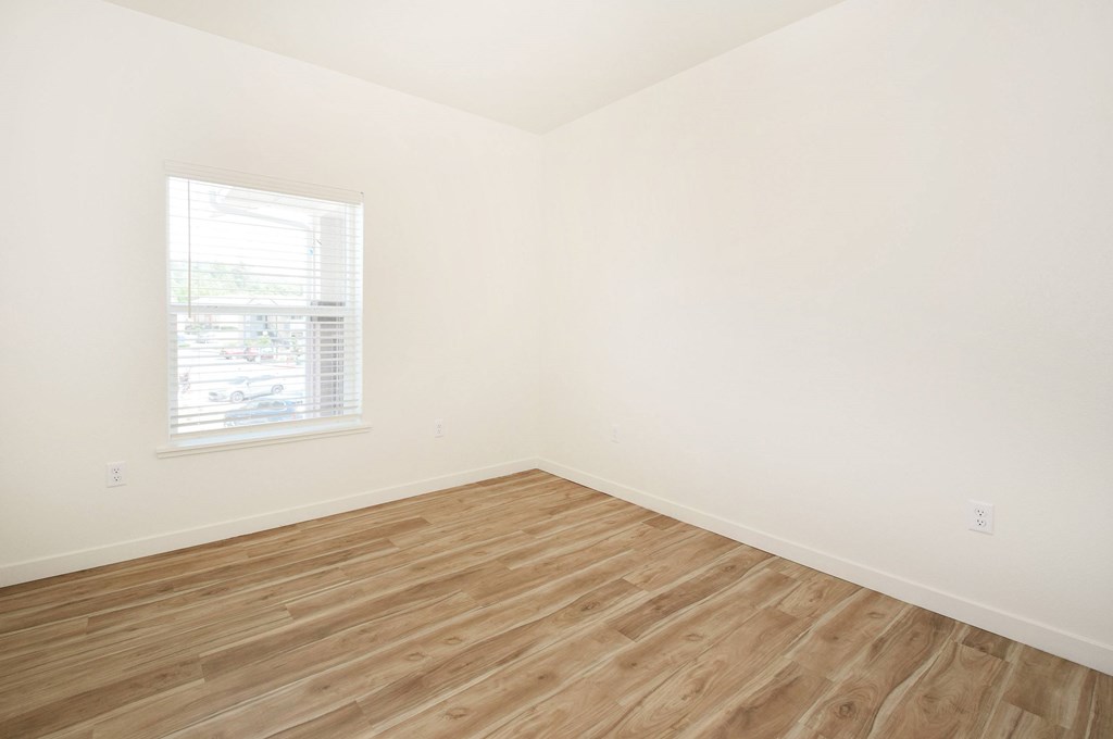 A room with wooden flooring and a window.