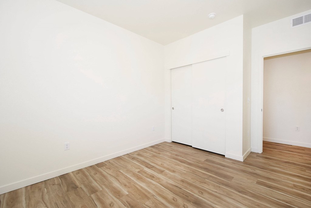 A room with a white door and wooden flooring.