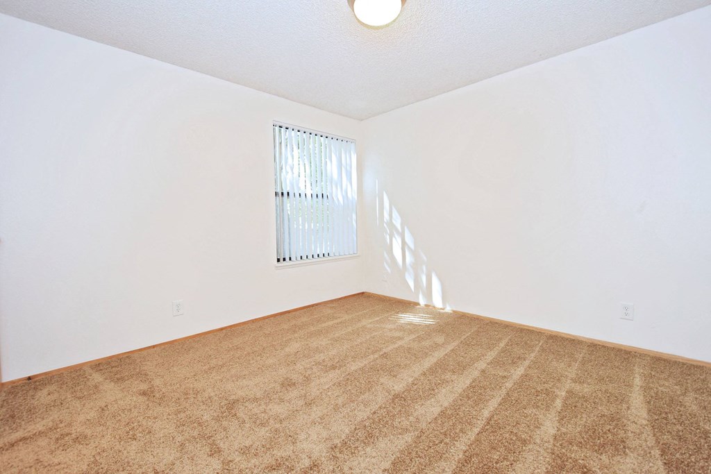 a bedroom with white walls and a window