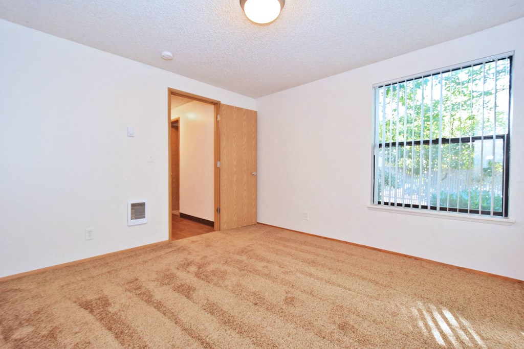 a bedroom with a large window and white walls