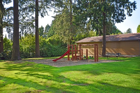 A playground with a red slide and a wooden structure.