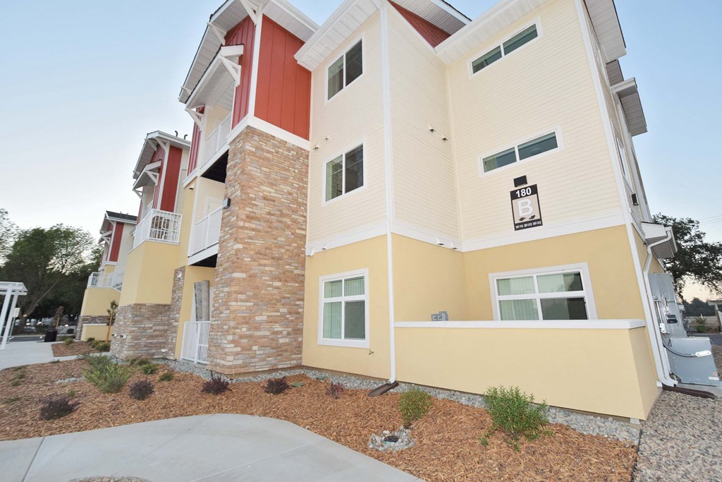an apartment building with yellow and red walls and a sidewalk