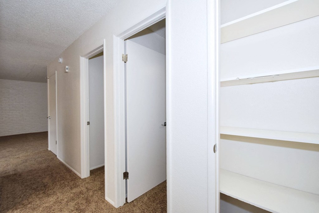 an empty bedroom with white closets and a carpeted floor