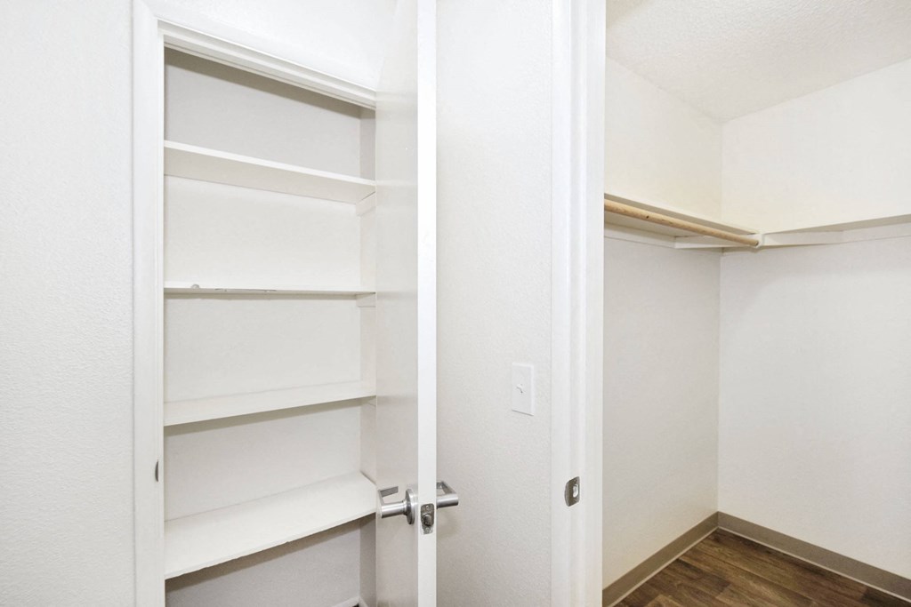 a room with white shelves and a door to a closet