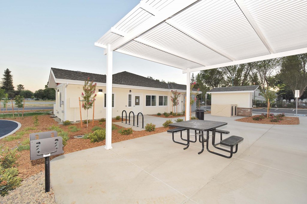 a covered patio with a table and chairs in front of a house